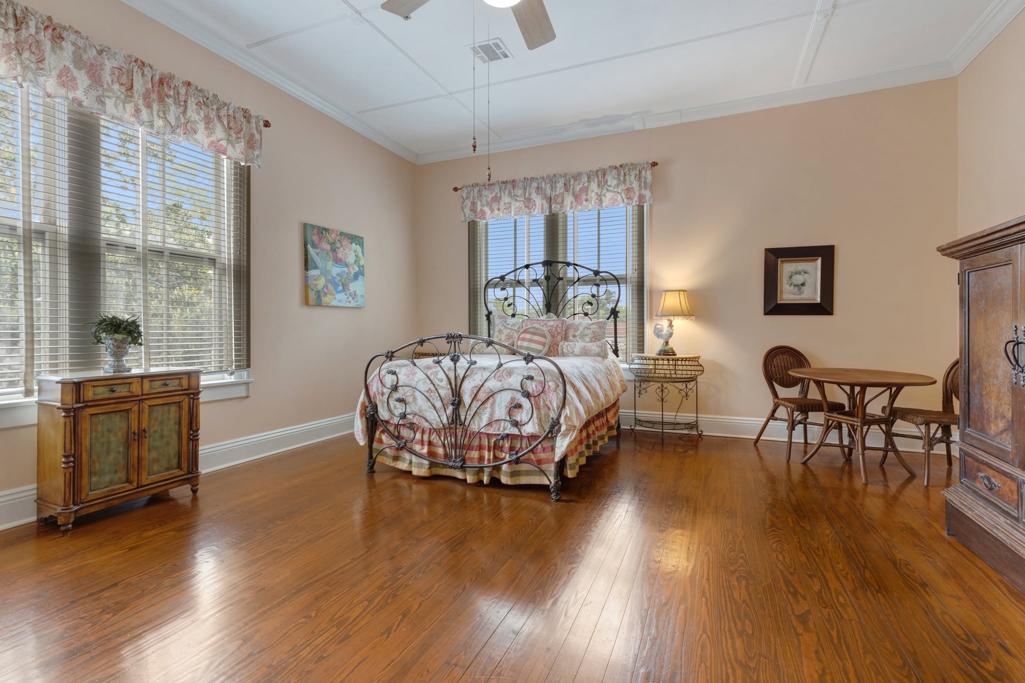 A guest room — a white iron bed and antique dresser in soft light