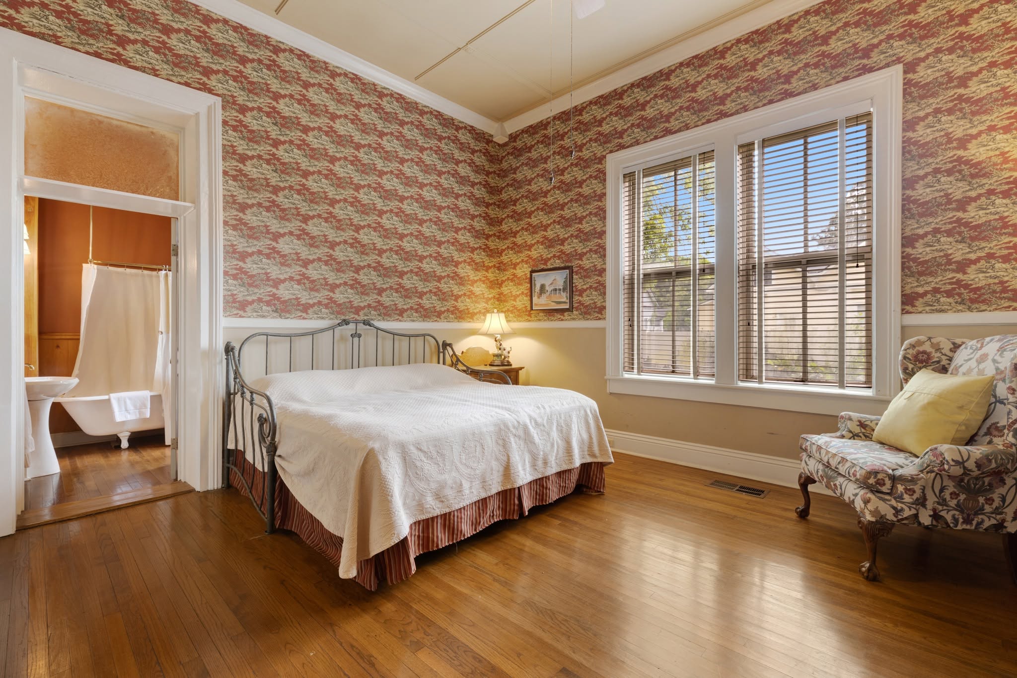 A guest room at The Caldwell House inn — antique bed and tall windows in soft light
