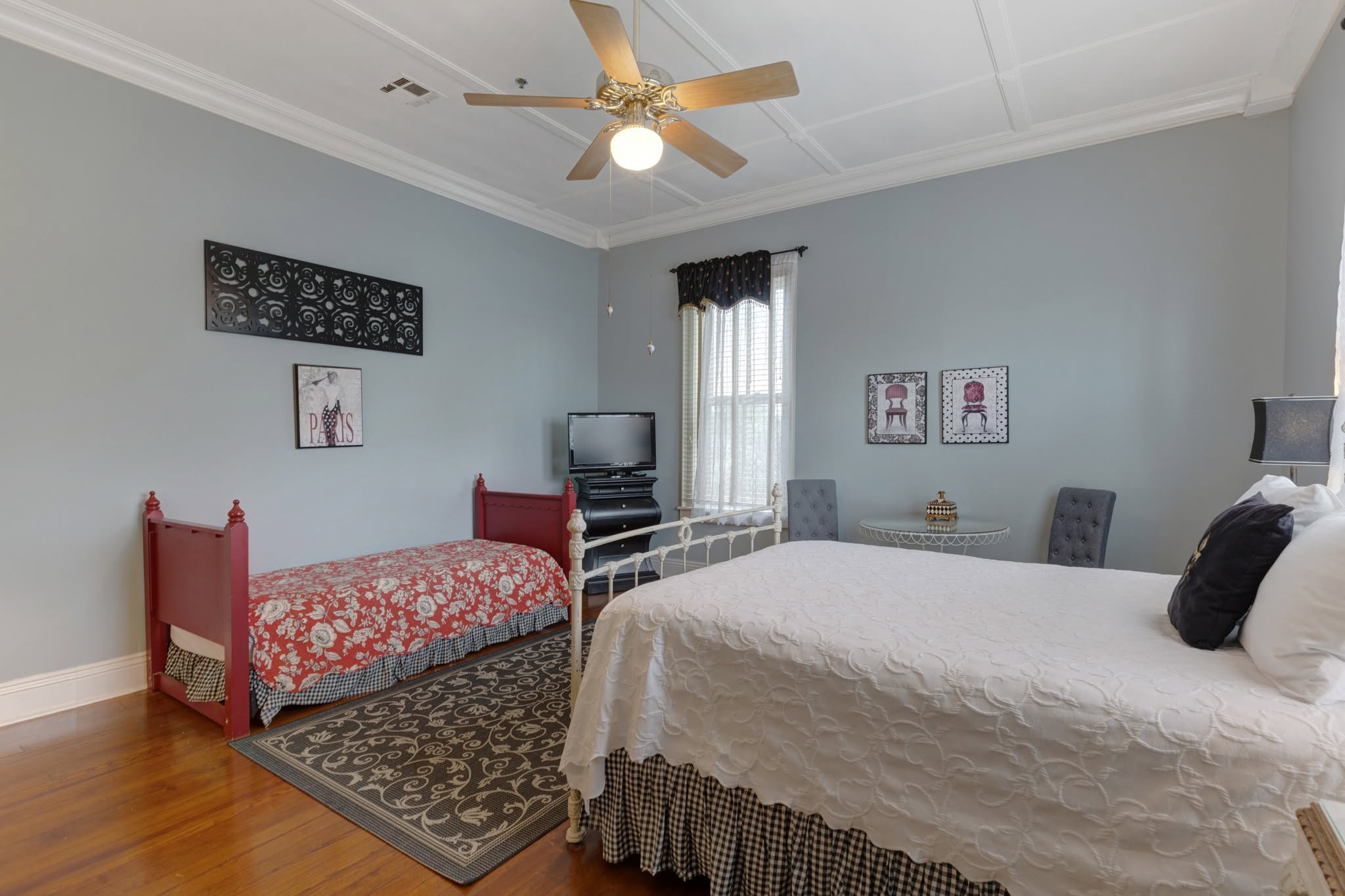 A guest room that sleeps the family — a queen bed and a second twin beneath a high coffered ceiling