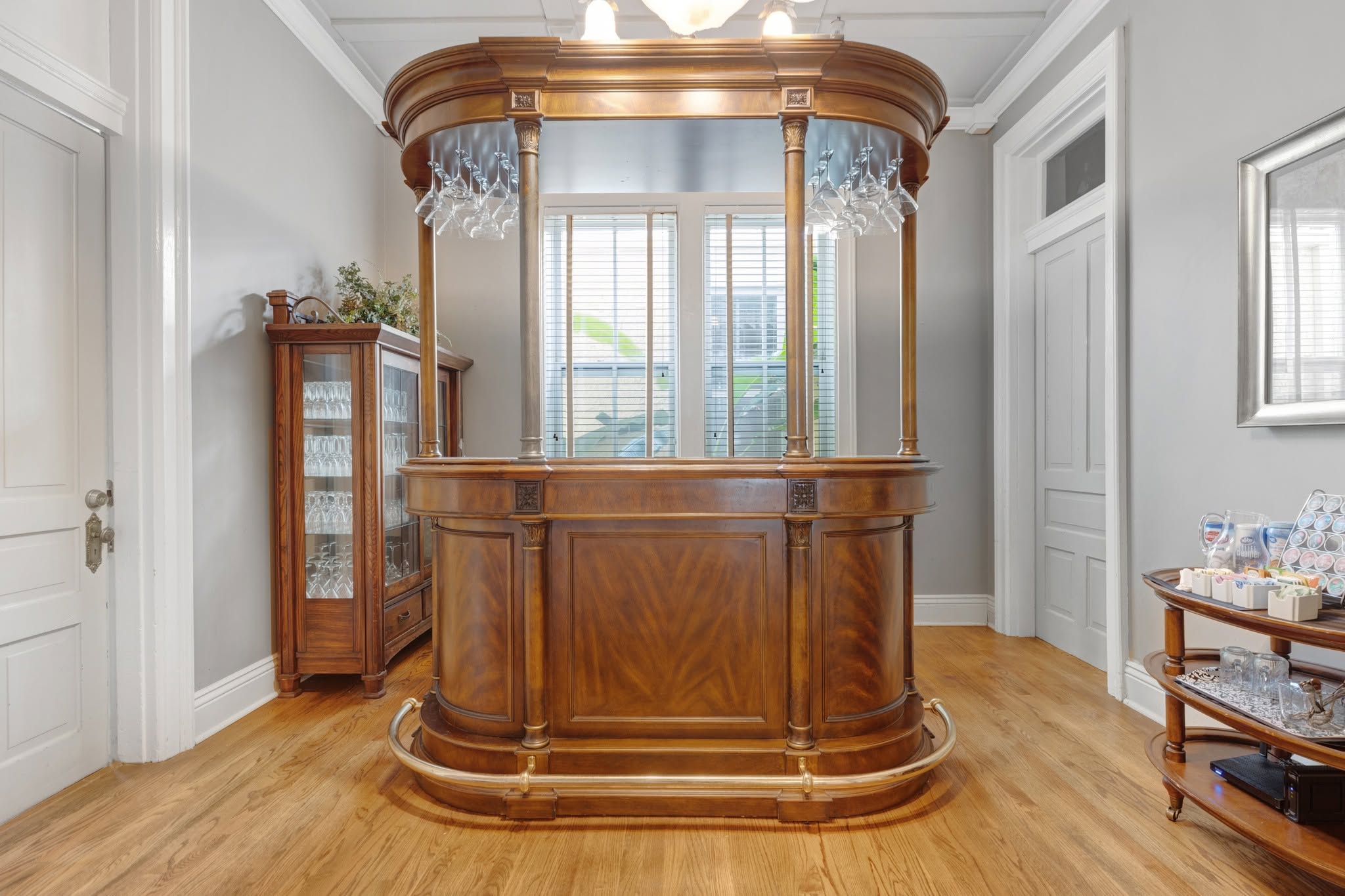 The antique mahogany bar, hung with stemware beneath a lit chandelier