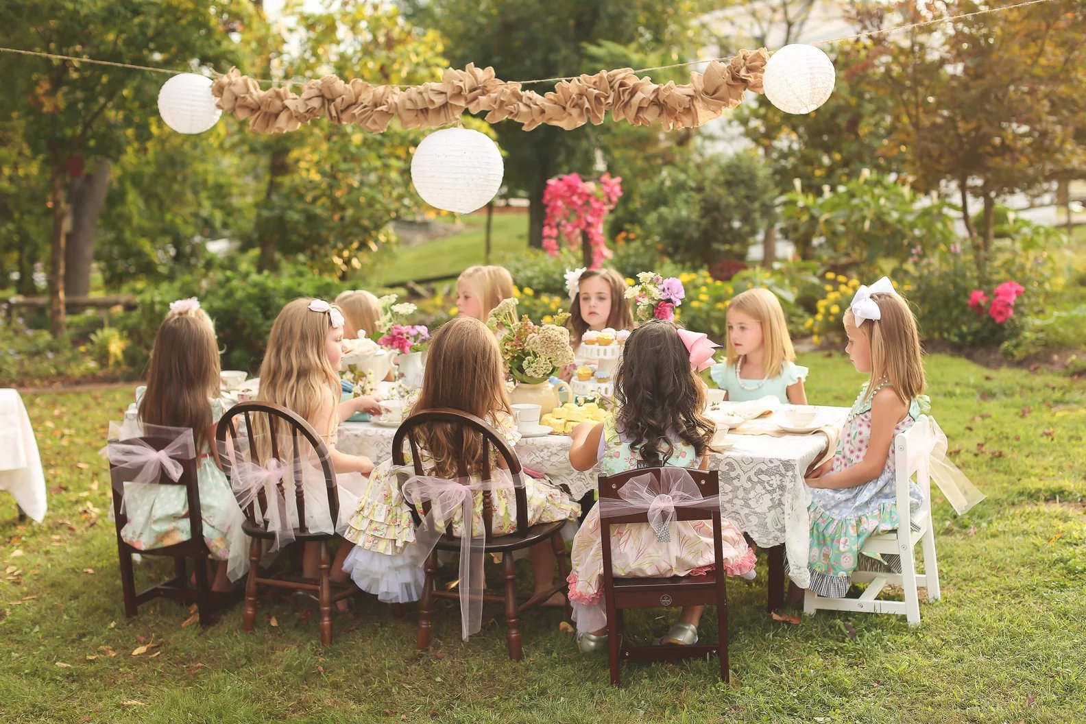 A garden party at The Caldwell House — a lace-laid table beneath the oaks with paper lanterns and florals