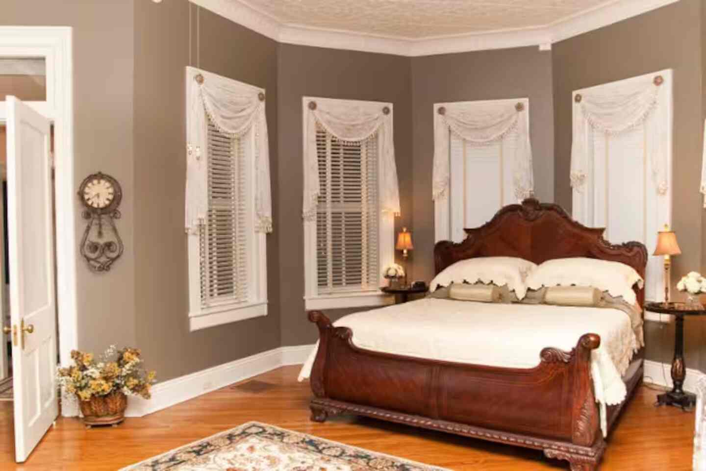 A Caldwell House guest room with a carved wood bed in soft bay-window light