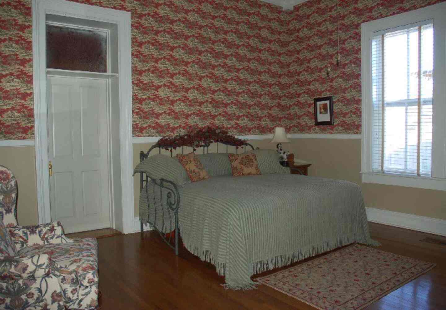 A light-filled guest room with a white iron bed