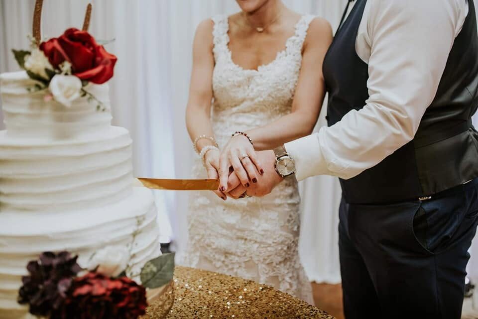 A couple cuts their tiered wedding cake at The Caldwell House
